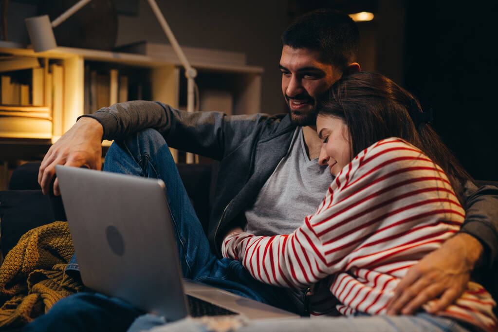 ζευγάρι απολαμβάνει το χρόνο μαζί στο σπίτι, χρησιμοποιώντας το laptop - Φωτογραφία, εικόνα