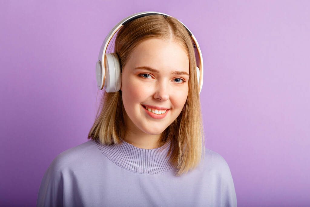 Happy Young nainen kuulokkeet muotokuva. Kaunis hymyilevä nainen blondi kampauksen nauttia kuunnella laulun musiikkia kuulokkeet eristetty violetti väri tausta. Kopioi tila - Valokuva, kuva