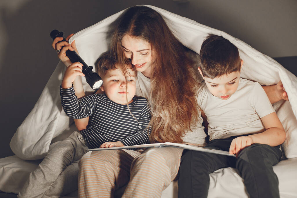 Mam en kind lezen een boek met een zaklamp - Foto, afbeelding