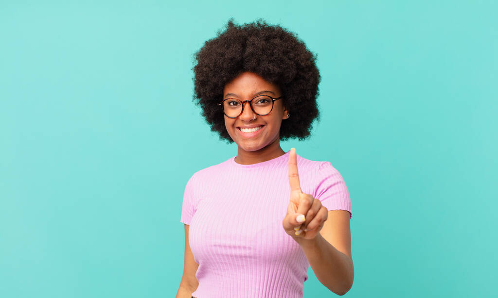 mujer negra afro sonriendo orgullosa y confiadamente haciendo la pose número uno triunfante, sintiéndose como un líder - Foto, imagen