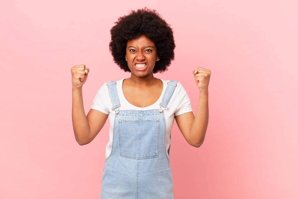 afro femme noire criant agressivement avec une expression en colère ou avec les poings serrés célébrant le succès - Photo, image