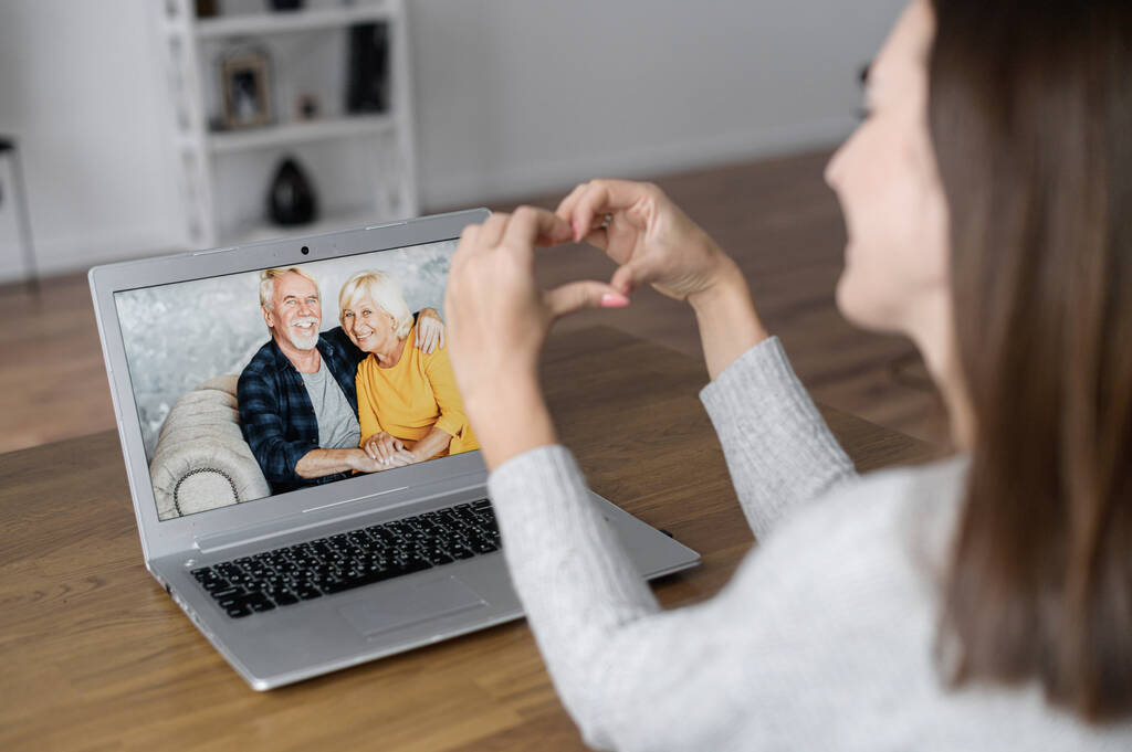Видеовстреча с бабушкой и дедушкой на ноутбуке, пожилая пара на экране - Фото, изображение