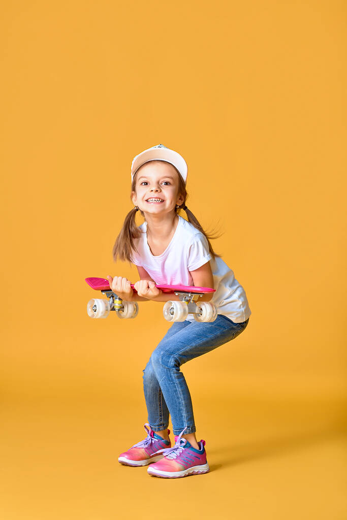 Κομψό αστείο κορίτσι που φοράει λευκό t-shirt, μπλε τζιν και αθλητικά παπούτσια - Φωτογραφία, εικόνα