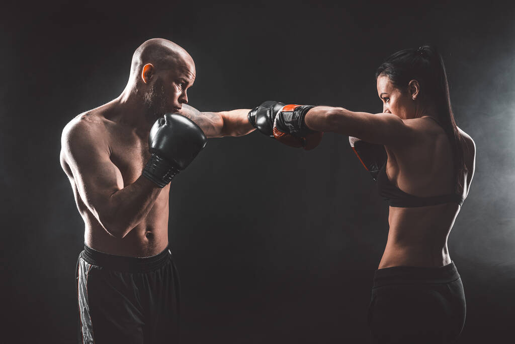 Üstsüz kadın boks antrenörüyle egzersiz yapıyor ve kendini savunuyor. - Fotoğraf, Görsel