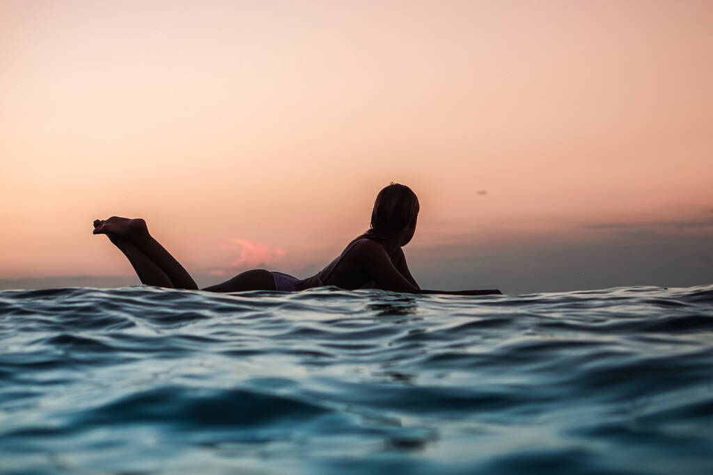 Portret z wody surferki z pięknym ciałem na desce surfingowej w oceanie o zachodzie słońca na Bali - Zdjęcie, obraz