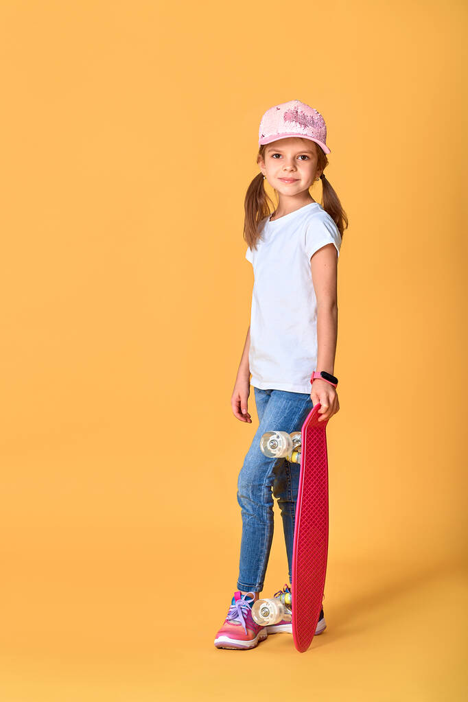 Stílusos vicces lány fehér pólóban, kék farmerban és tornacipőben - Fotó, kép