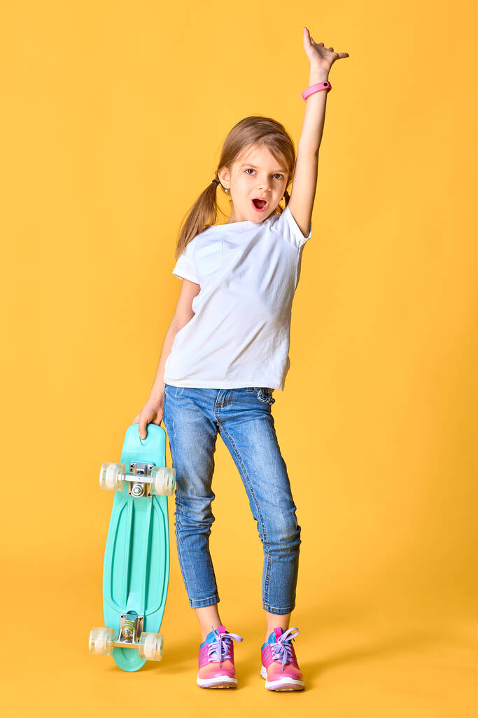 Elegante chica divertida con camiseta blanca, vaqueros azules y zapatillas de deporte - Foto, imagen