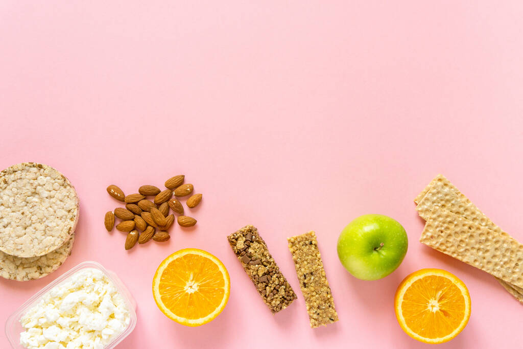 Плоская укладка различных здоровых закусок на розовом фоне, пространство для текста - Фото, изображение