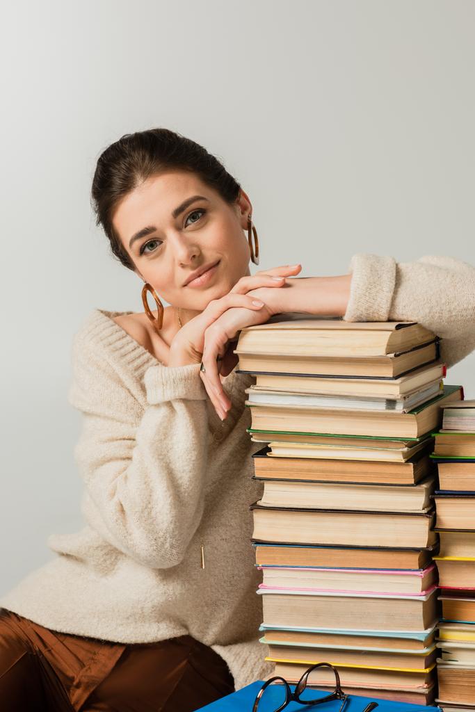 young woman in earrings leaning on stack of books isolated on white - Photo, Image