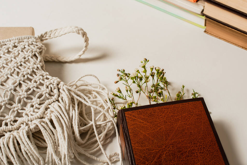 полевые цветы в книжке с твердой обложкой рядом с вязаной сумкой на белом - Фото, изображение