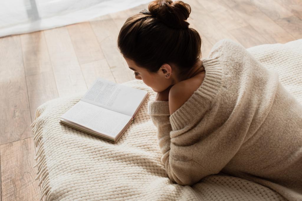 mladá žena čtení román zatímco odpočívá na posteli doma - Fotografie, Obrázek