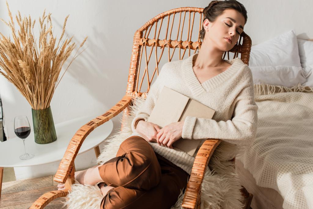 junge Frau schläft im Schaukelstuhl mit Buch  - Foto, Bild
