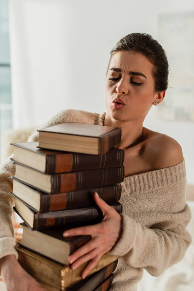 młoda kobieta patrząc na stos książek w domu - Zdjęcie, obraz