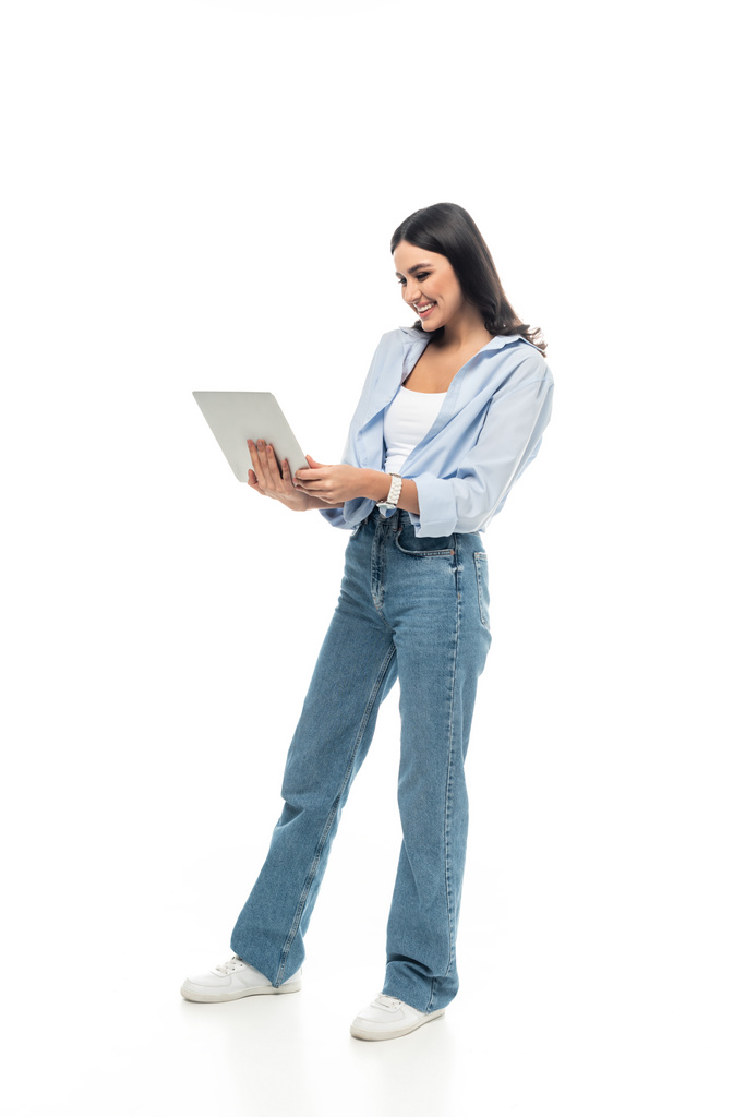 Вид в полный рост бизнесвумен в повседневной одежде, держащей ноутбук на белом фоне - Фото, изображение