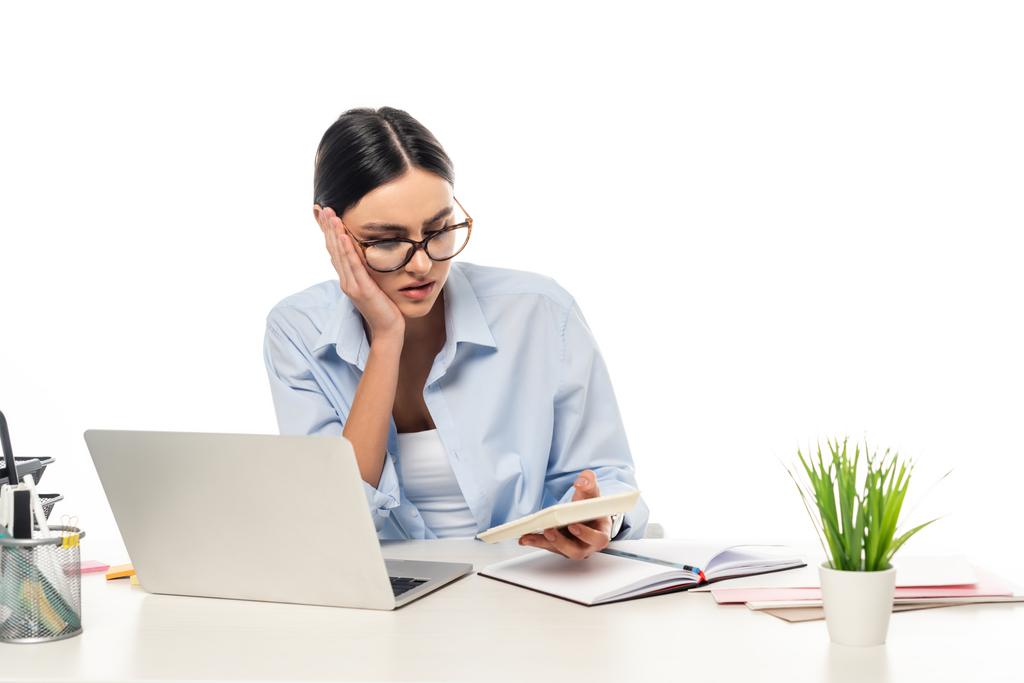 pensativa mujer de negocios que trabaja con la calculadora cerca del ordenador portátil aislado en blanco - Foto, Imagen