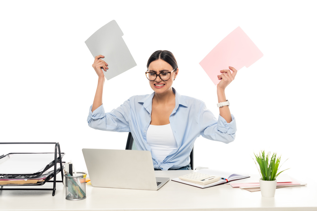 irritato donna d'affari in possesso di cartelle mentre seduto vicino al computer portatile isolato su bianco - Foto, immagini
