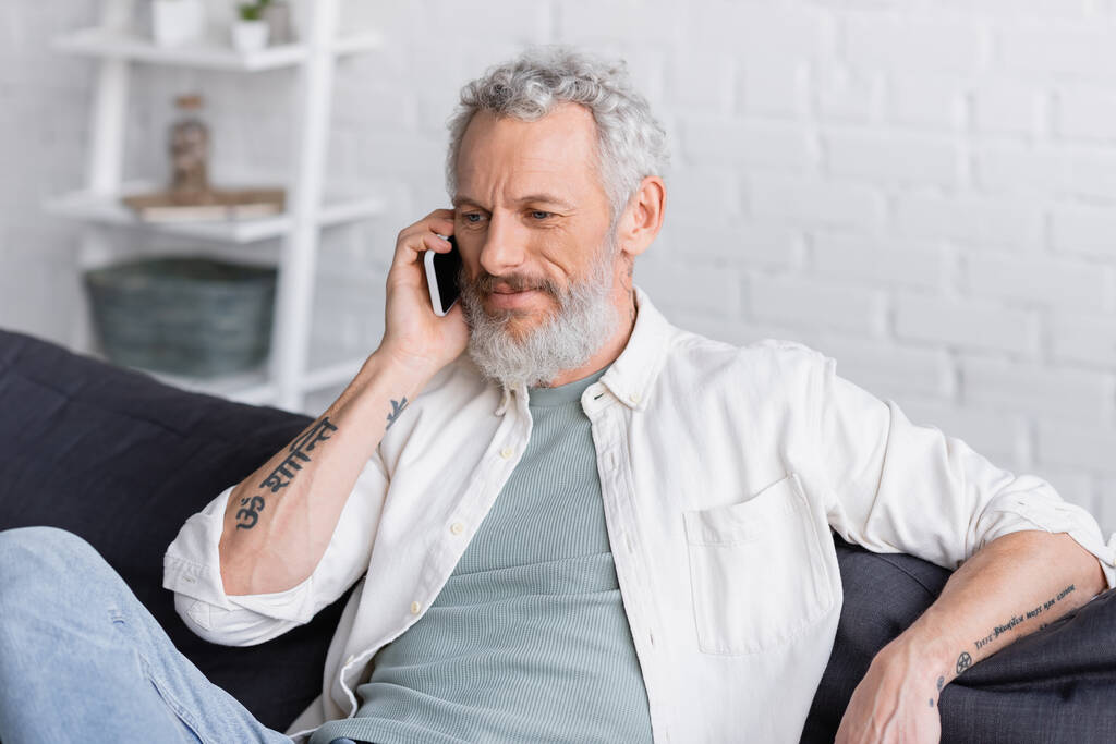 vousatý a potetovaný muž mluví na smartphonu  - Fotografie, Obrázek