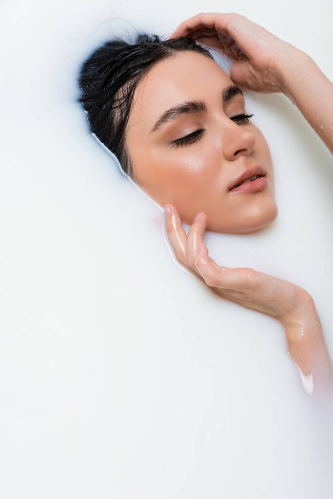pretty young woman touching face while taking milk bath - Photo, Image