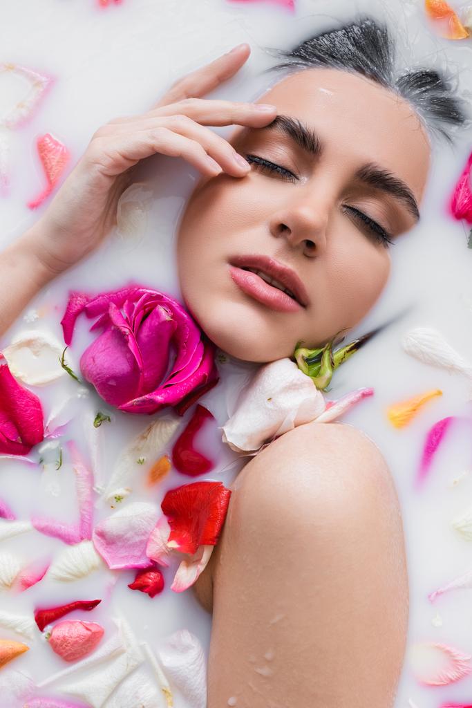 vue de dessus de la femme sensuelle toucher le visage tout en prenant un bain floral avec du lait - Photo, image