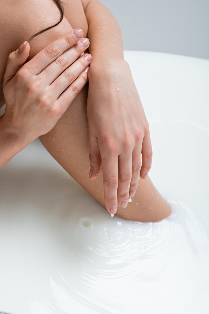 visão parcial da mulher tocando na perna enquanto toma banho de leite - Foto, Imagem