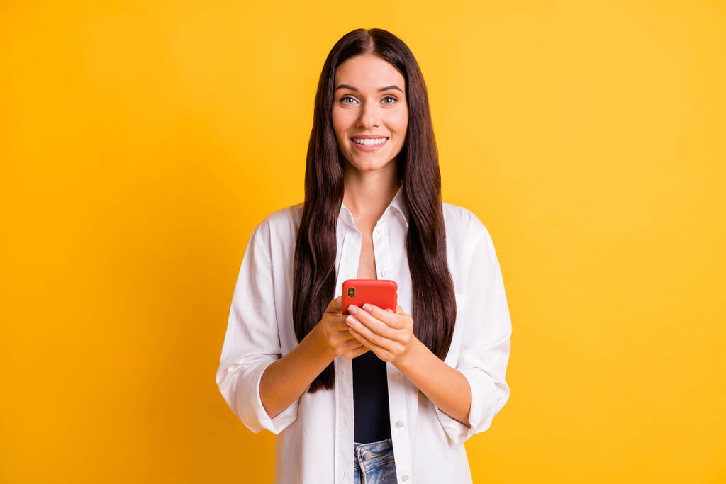 Foto de adorável senhora positiva radiante sorriso olhar câmera segurar telefone isolado no fundo de cor amarela - Foto, Imagem