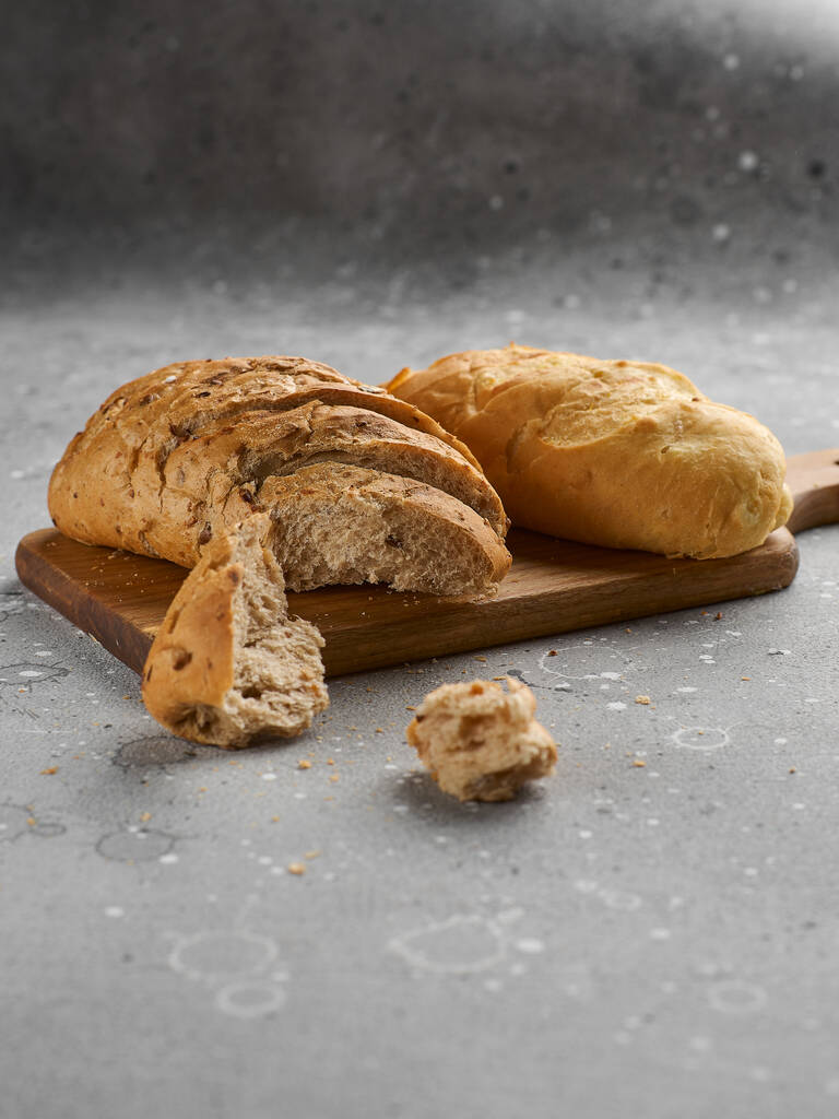 Buchty se semínky a zrním na kamenné textuře. Čerstvý rustikální křupavý chleba na dřevěné desce. Zdravá, chutná, výživná svačinka. Odnést jídlo - Fotografie, Obrázek