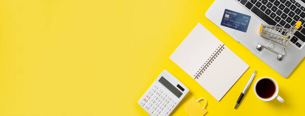 オンラインショッピングのコンセプト。オフィスの黄色のテーブルの背景に孤立ノート、計算機やコンピュータとクレジットカードの購入デザインコンセプトのトップビュー. - 写真・画像