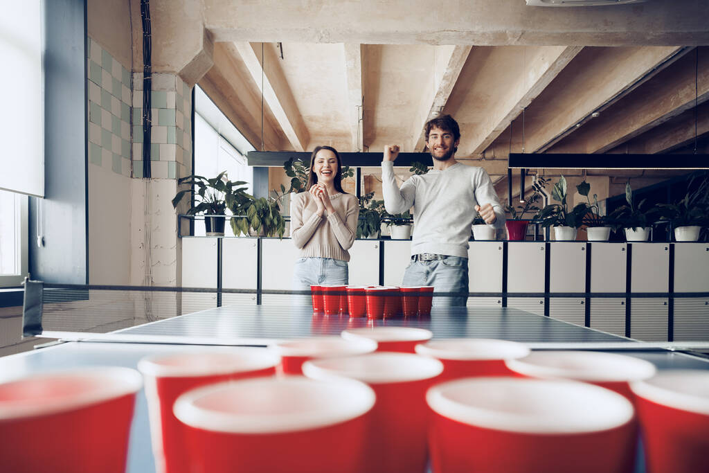 Junge Mitarbeiter spielen Bier-Pong im modernen Büro - Foto, Bild