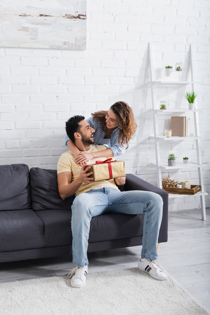 excited muslim man holding wrapped present near caring girlfriend  - Photo, Image
