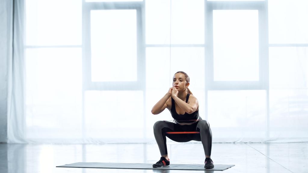 молодая брюнетка женщина упражнения с сопротивлением полосы в тренажерном зале  - Фото, изображение