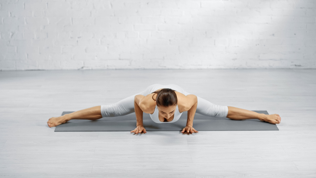 Mujer haciendo handstand y split en yoga mat  - Foto, Imagen