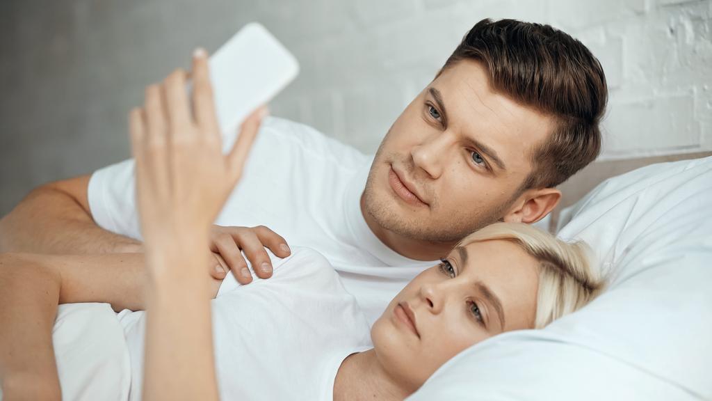 young man and woman taking selfie on smartphone in bedroom  - Photo, Image