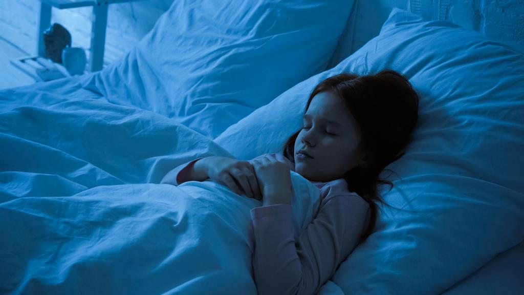 Dziecko śpiące na łóżku z białą pościelą w nocy  - Zdjęcie, obraz