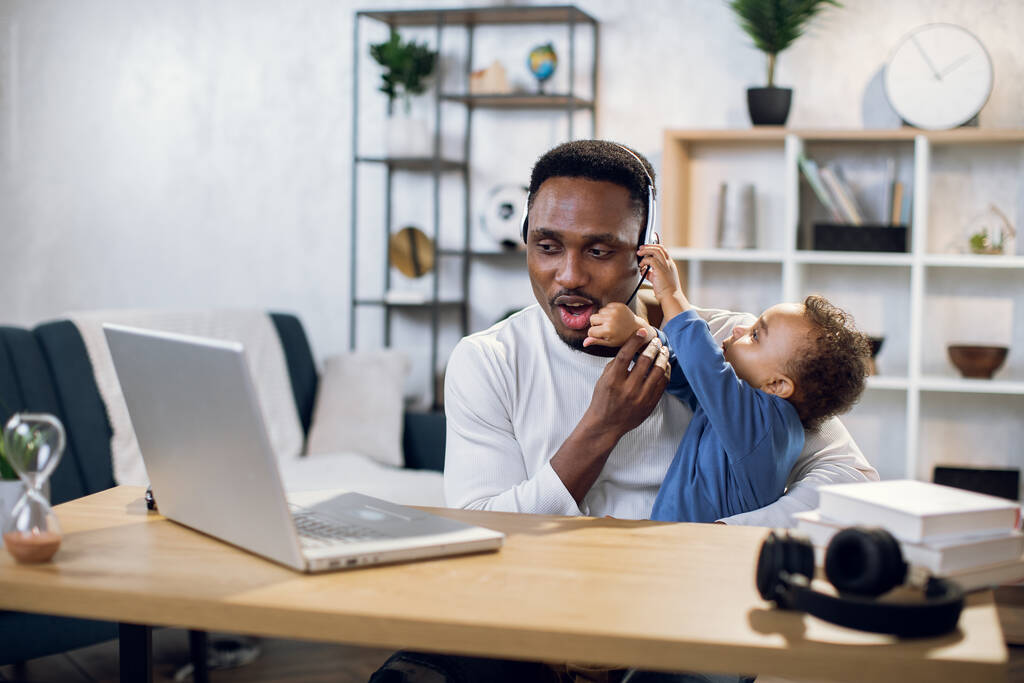 African man having video chat on laptop with baby on hands - Photo, Image