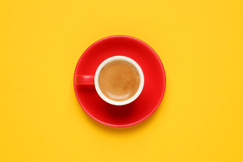 Café aromático en taza roja sobre fondo amarillo, vista superior - Foto, imagen
