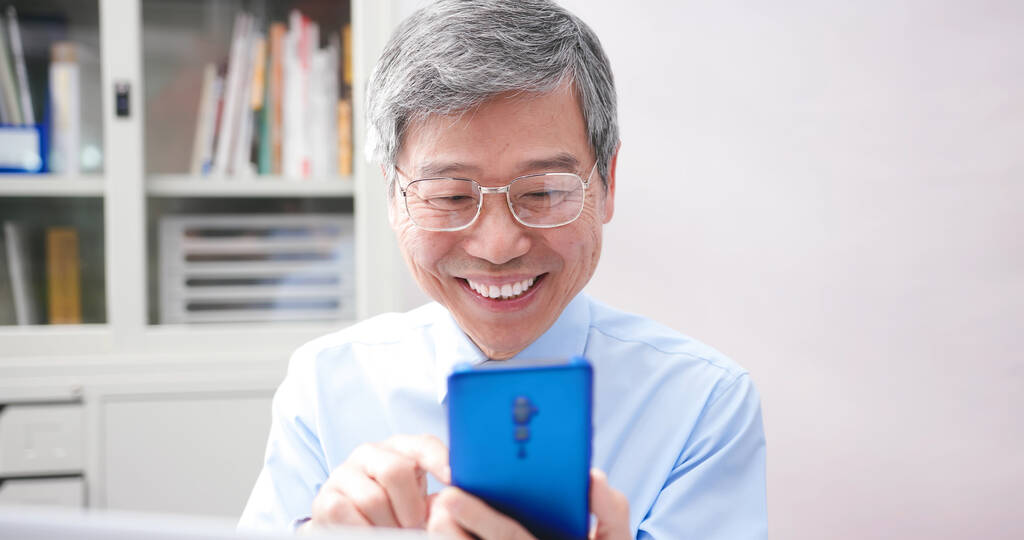 Ältere asiatische Geschäftsleute nutzen Smartphone gerne im Büro - Foto, Bild