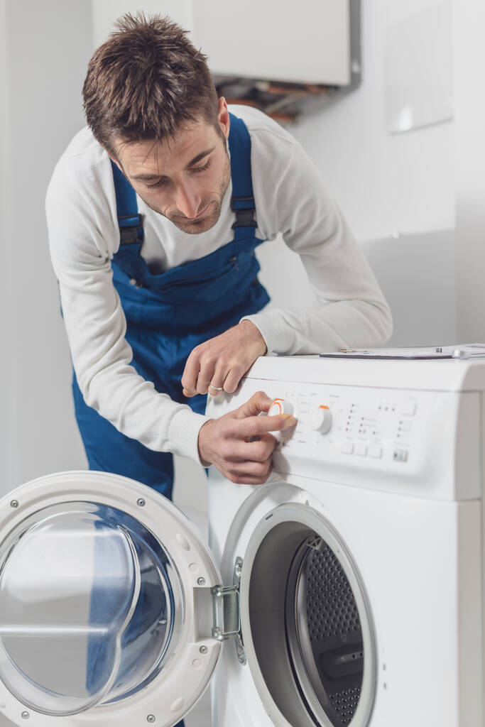 Reparateur repariert eine Waschmaschine, er justiert einen Knopf, professionelles Servicekonzept - Foto, Bild