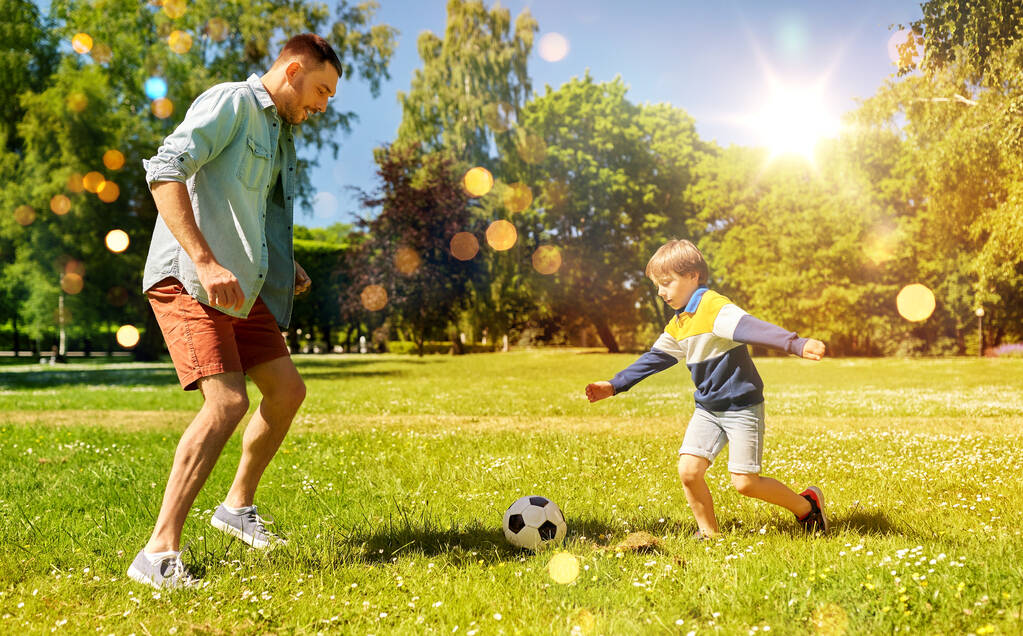 πατέρας με μικρό γιο παίζουν ποδόσφαιρο στο πάρκο - Φωτογραφία, εικόνα