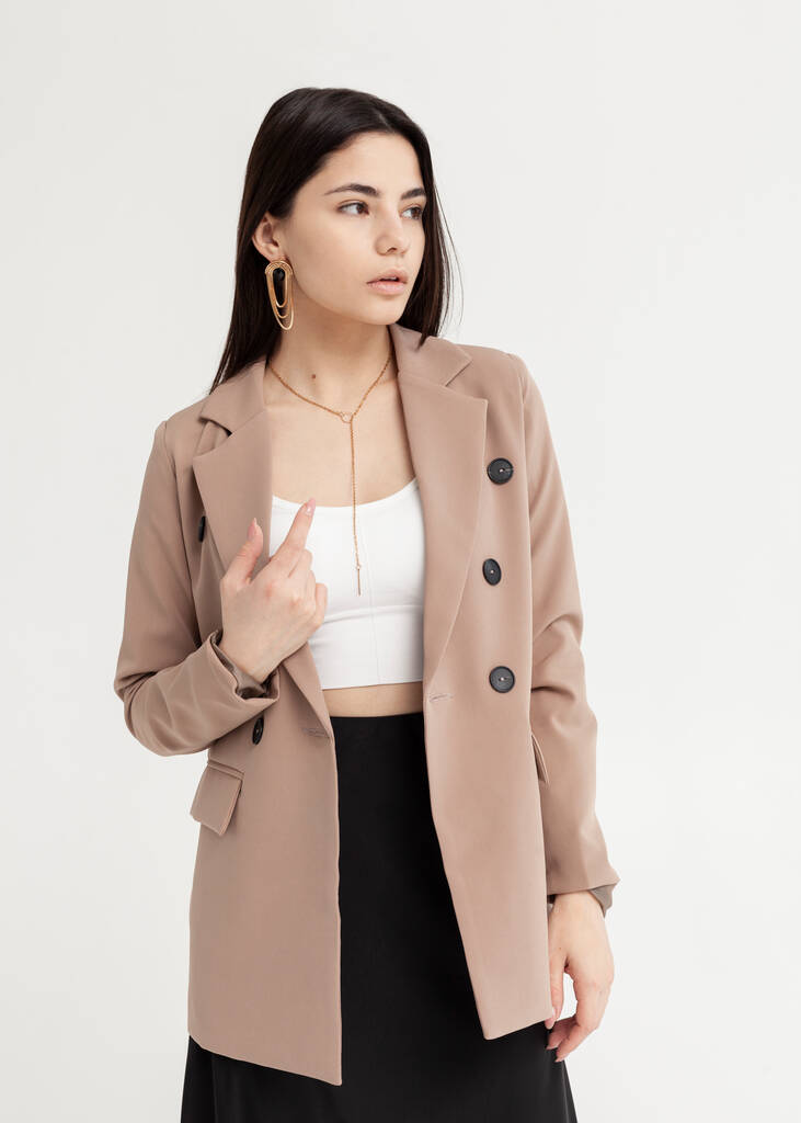 mooie brunette in een jas en zomer kleding op een lichte achtergrond - Foto, afbeelding