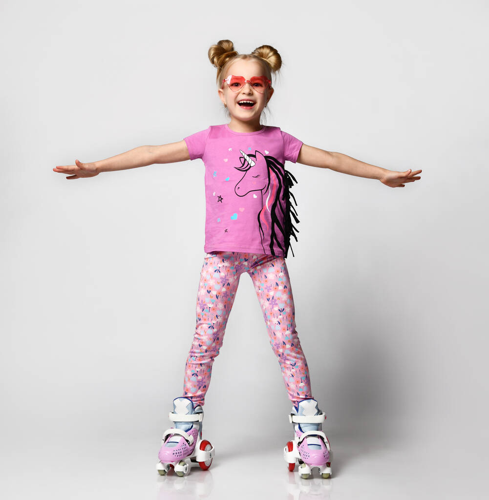 Portrait corporel complet d'une fille funky apprenant à rouler sur des patins à roulettes en studio - Photo, image