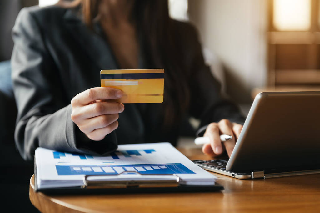 Mobil ödemeler için akıllı telefon kullanan bir kadın çevrimiçi alışveriş, Omni kanalı, masada oturan, sabah ışıklarında sanal simge grafik arayüzü ekranı - Fotoğraf, Görsel