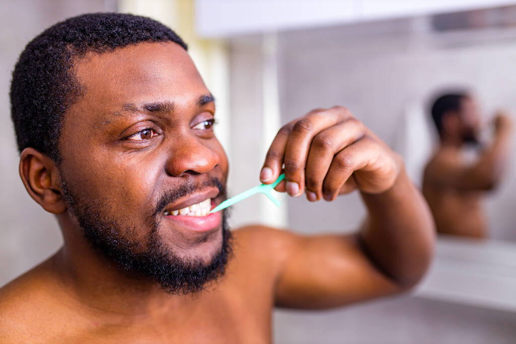 Afrykański Amerykanin myjący zęby nicią dentystyczną - Zdjęcie, obraz