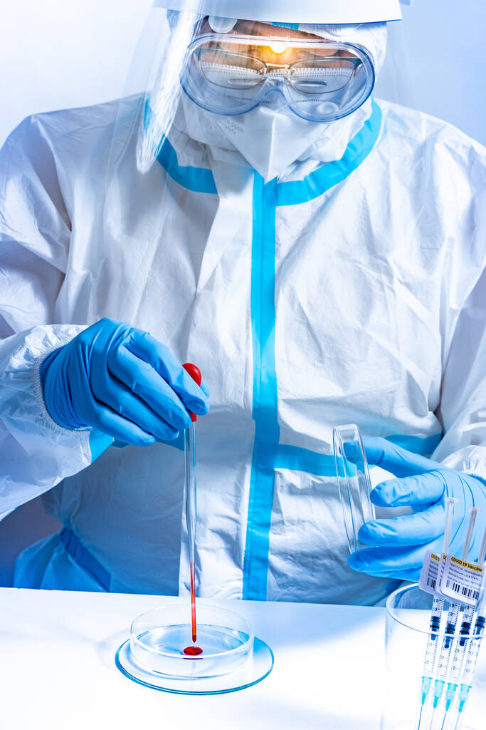 Lékařská laboratoř s vybavením a mikrobiolog nošení pyžama, obličejový štít masky, pracuje s Petriho misky pipety, různé tkáně a vzorky krve. Vývoj vakcíny, výzkum léčiv. - Fotografie, Obrázek