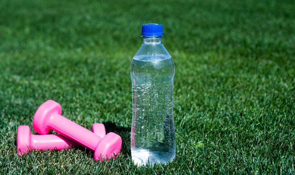 butelka wody i sztangi fitness na zielonej trawie, nawilżenie - Zdjęcie, obraz