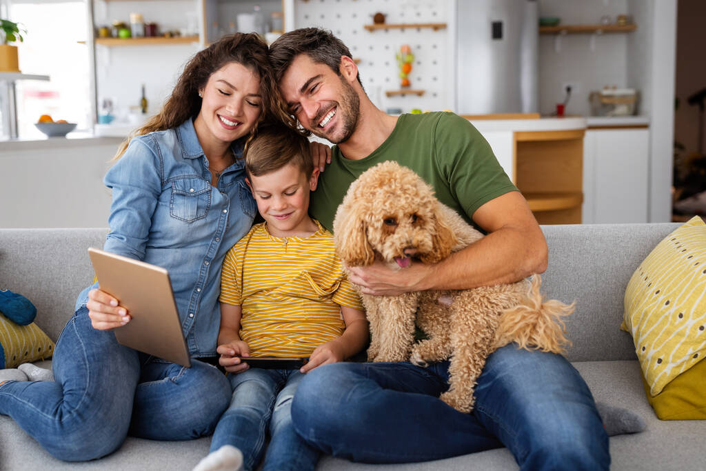 Felice giovane famiglia con dispositivi moderni e cane divertirsi, giocando a casa - Foto, immagini
