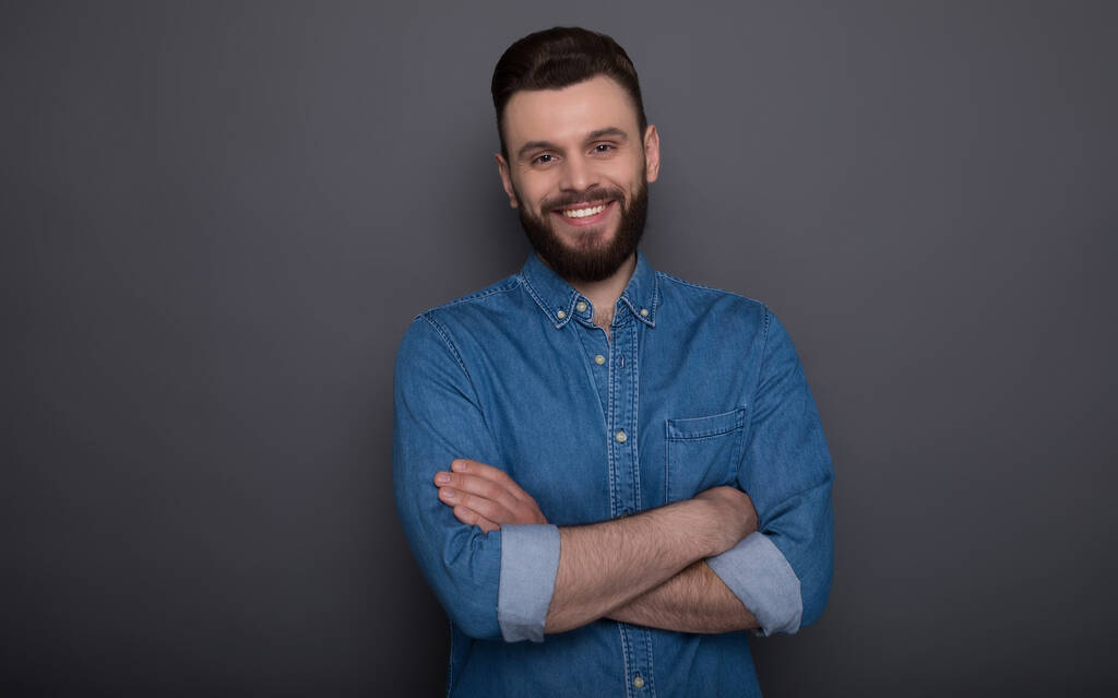 Крупним планом фото збудженого щасливого молодого сучасного бородатого хіпстера в джинсах одягнені ізольовані на сірому фоні
  - Фото, зображення