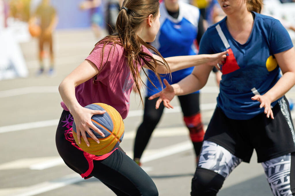 Молодые девушки играют в уличный баскетбол летом. Момент борьбы за владение мячом. - Фото, изображение