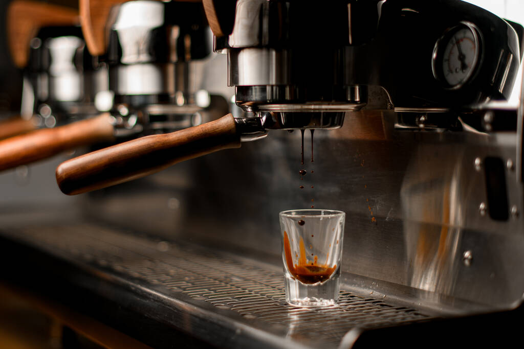 professionele koffiezetapparaat bereidt en schenkt automatisch koffiedrank in transparant glas - Foto, afbeelding