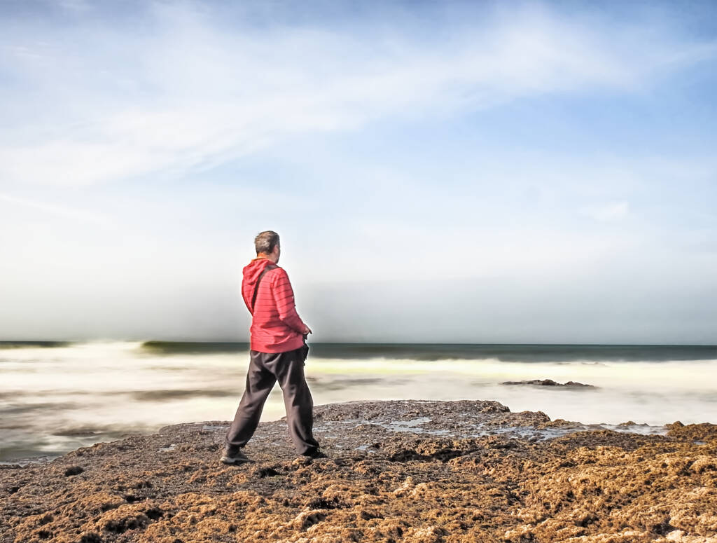Um homem irreconhecível em pé na praia e admirando a vista hipnotizante da paisagem marinha - Foto, Imagem