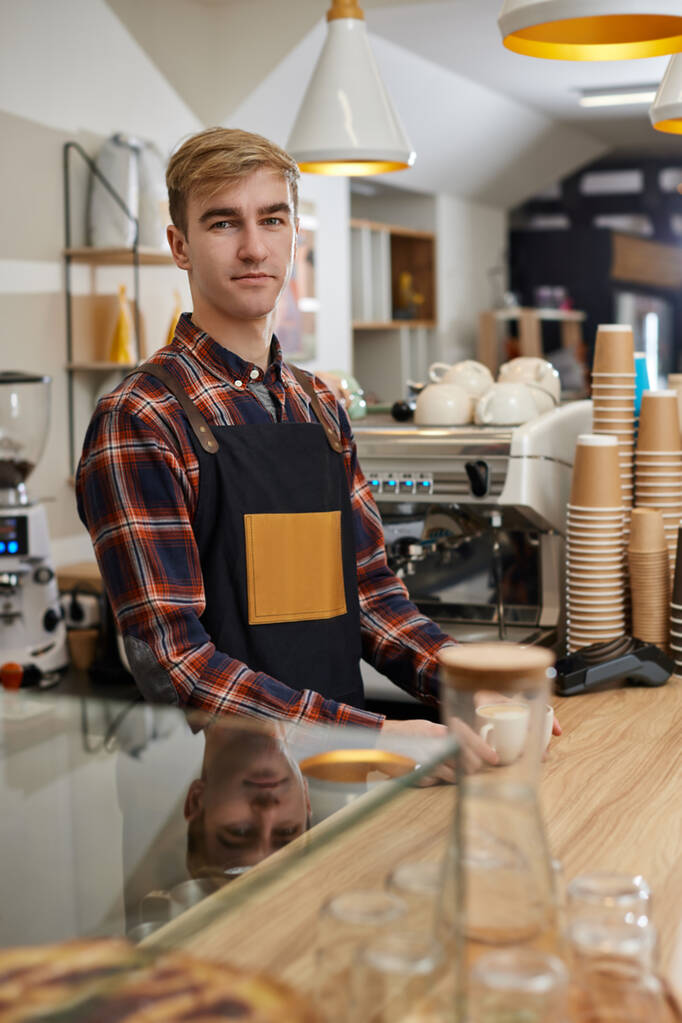 waiter in apron in coffee shop, barista is happy to work in the cafeteria - Photo, Image